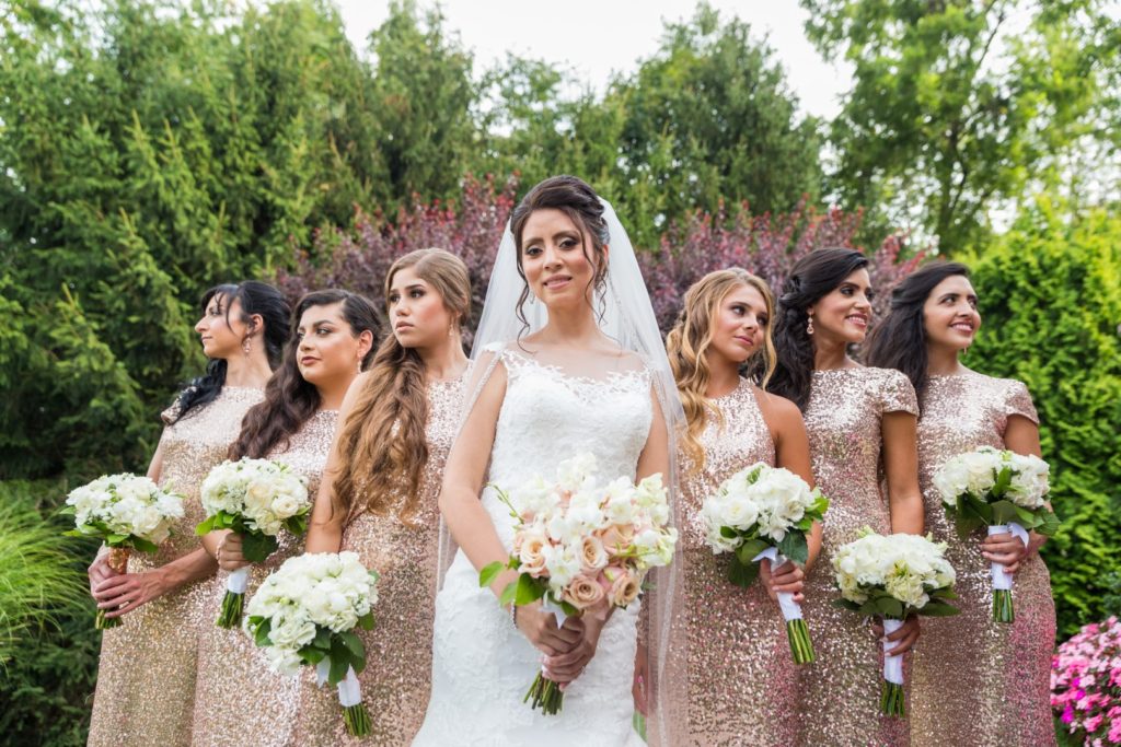 Entire bridal party poses together, bridesmaids hold hot pink parasols